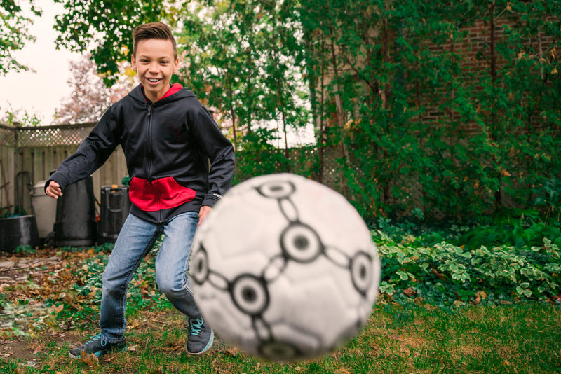 kid playing with football in garden
